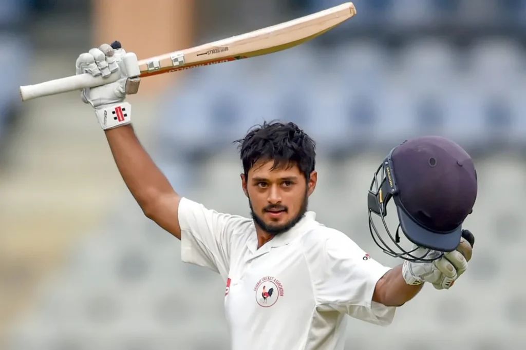 Priyank Panchal walking off the field, raising his bat to acknowledge the crowd during his final first-class innings